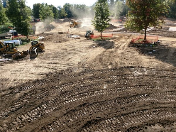 A group of construction vehicles are working on a dirt field.