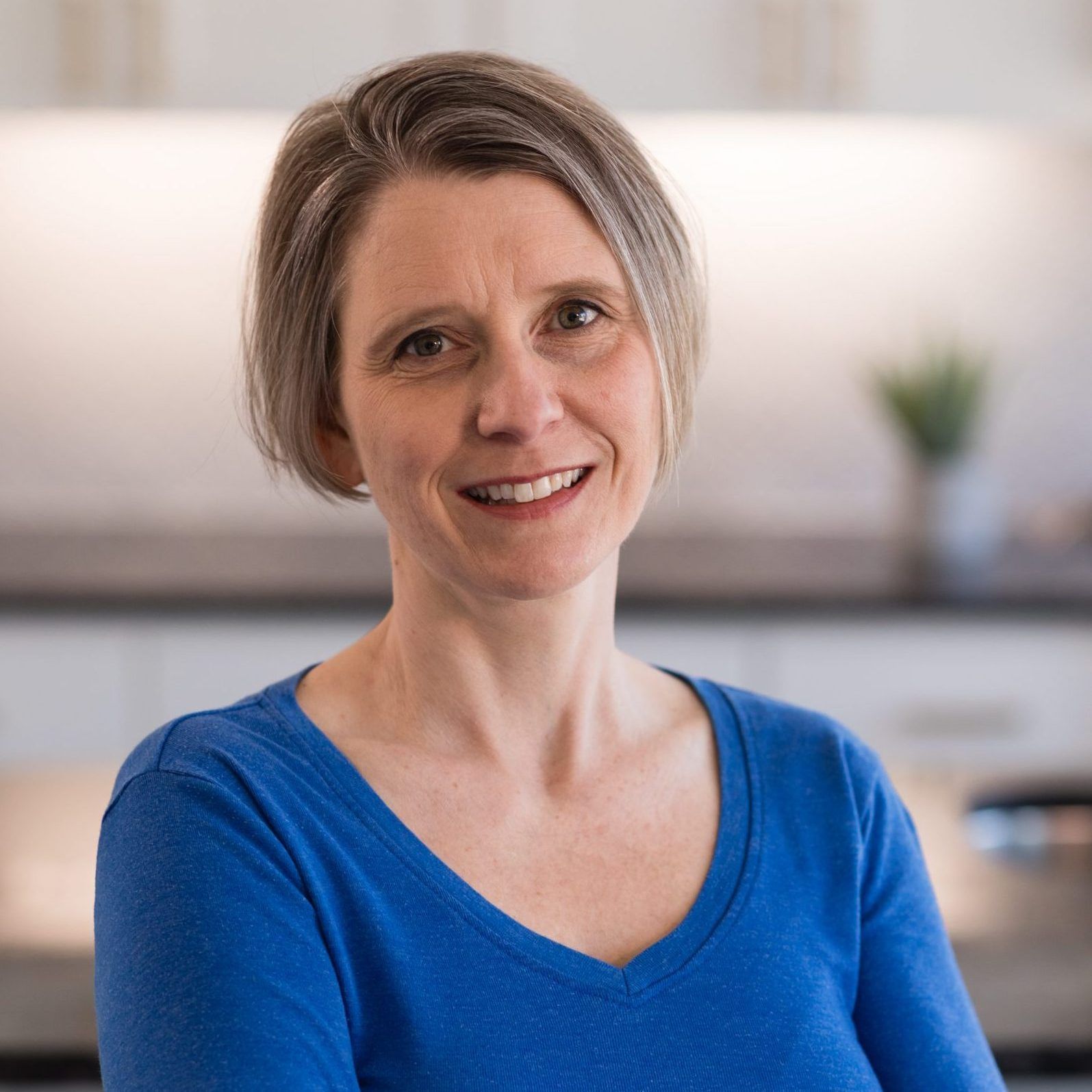 A woman in a blue shirt is smiling for the camera.