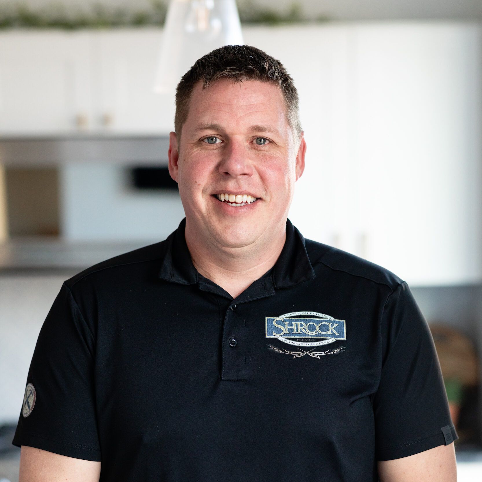 A man wearing a black shirt with the Shrock logo on it.