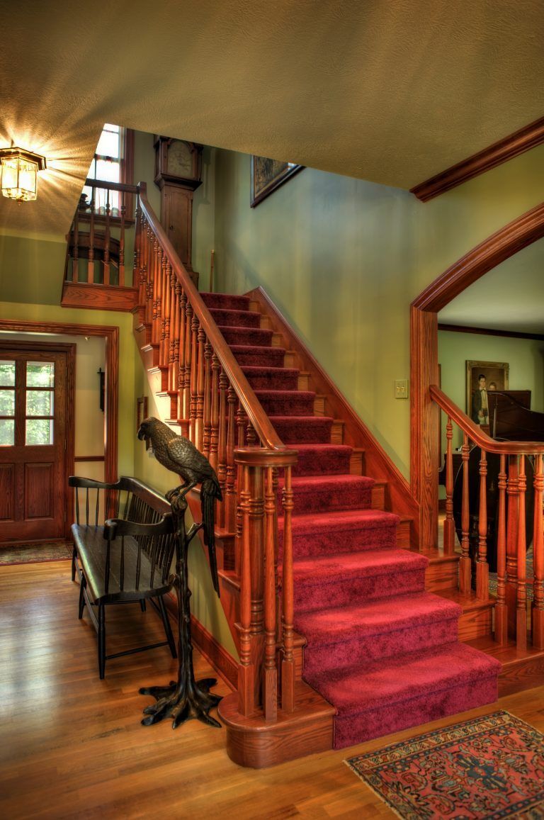 A staircase with a red carpet and a wooden railing.