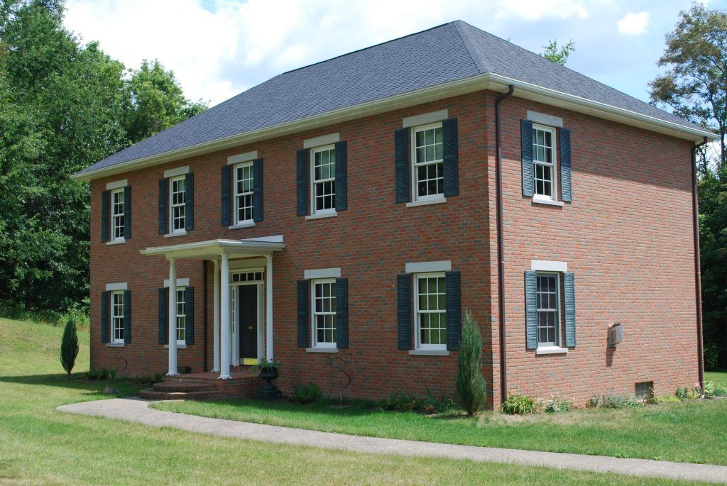 A large brick house with blue shutters on the windows.