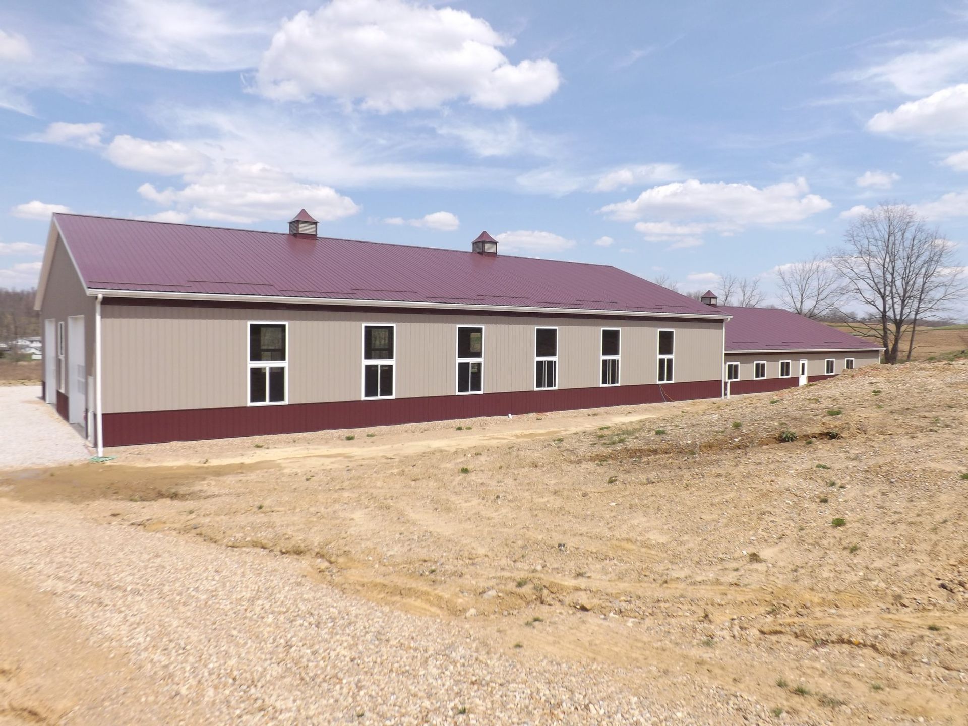 A large building with a purple roof is in the middle of a dirt field.