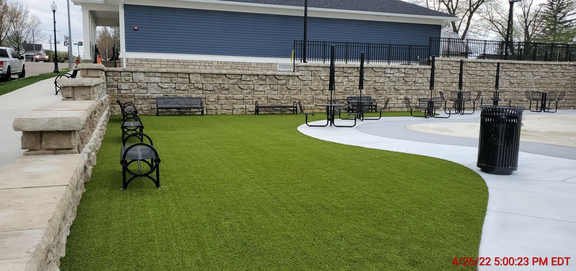 A park with benches and a trash can in it