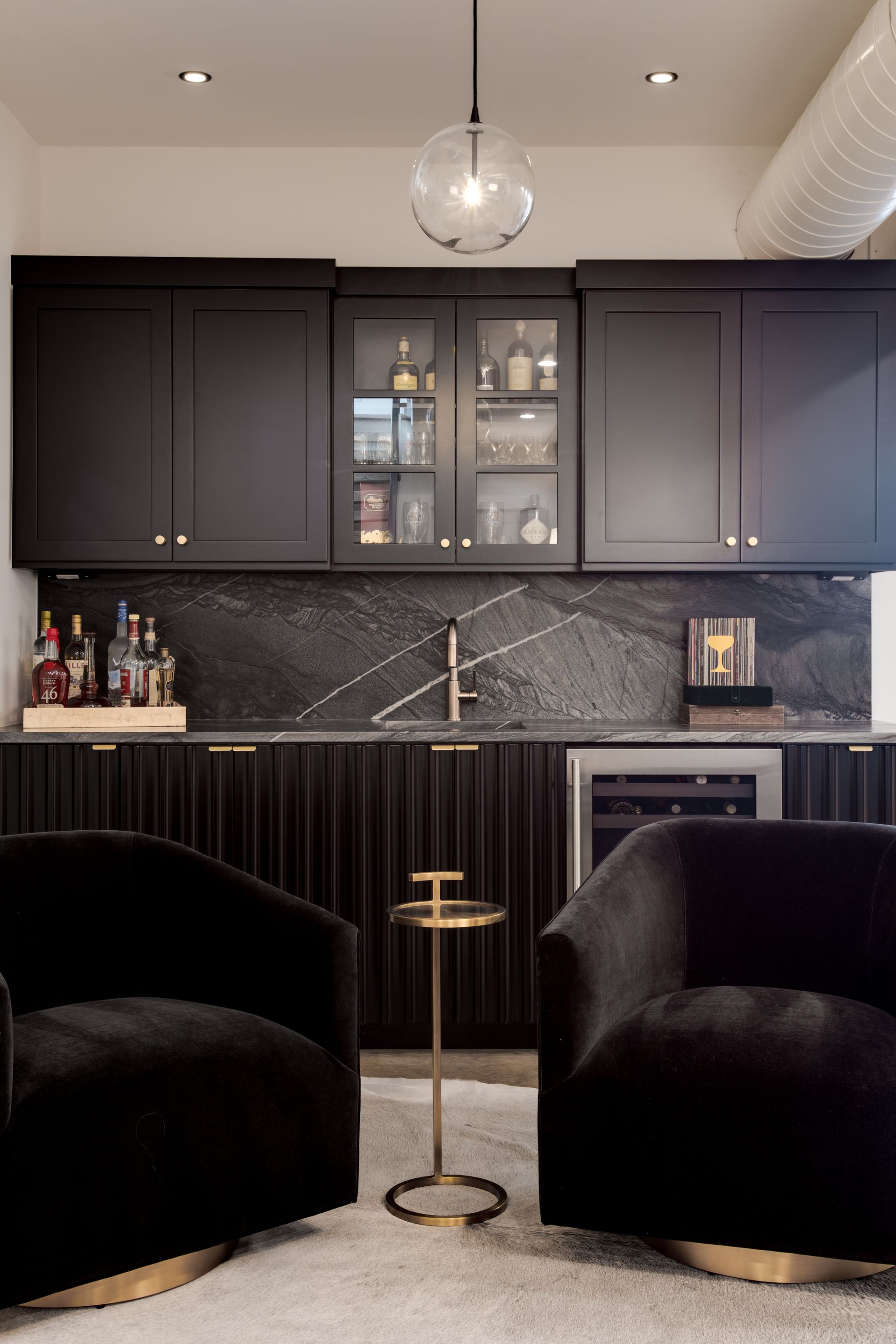 A kitchen with black cabinets and two black chairs.