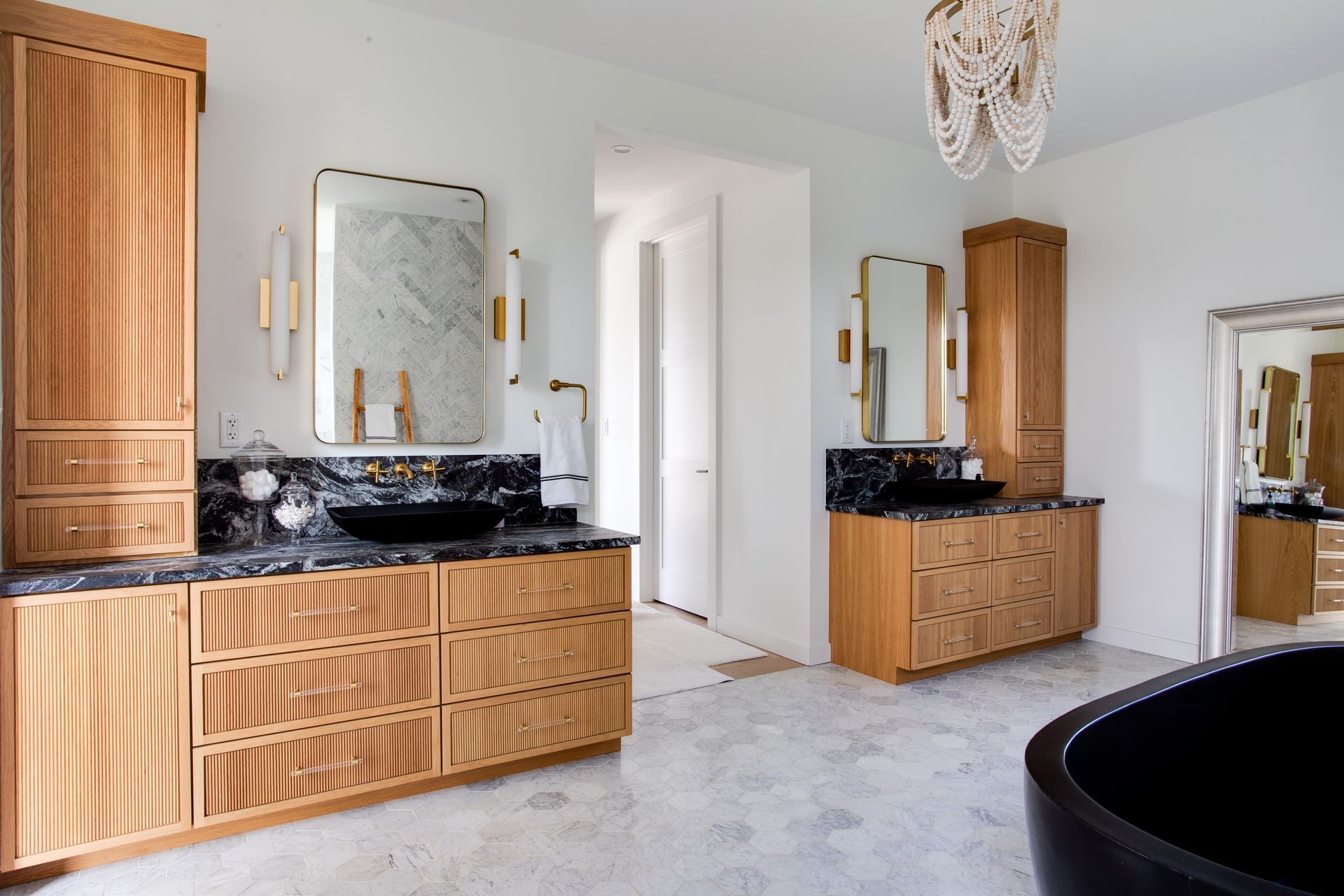 A bathroom with two sinks and a black tub.