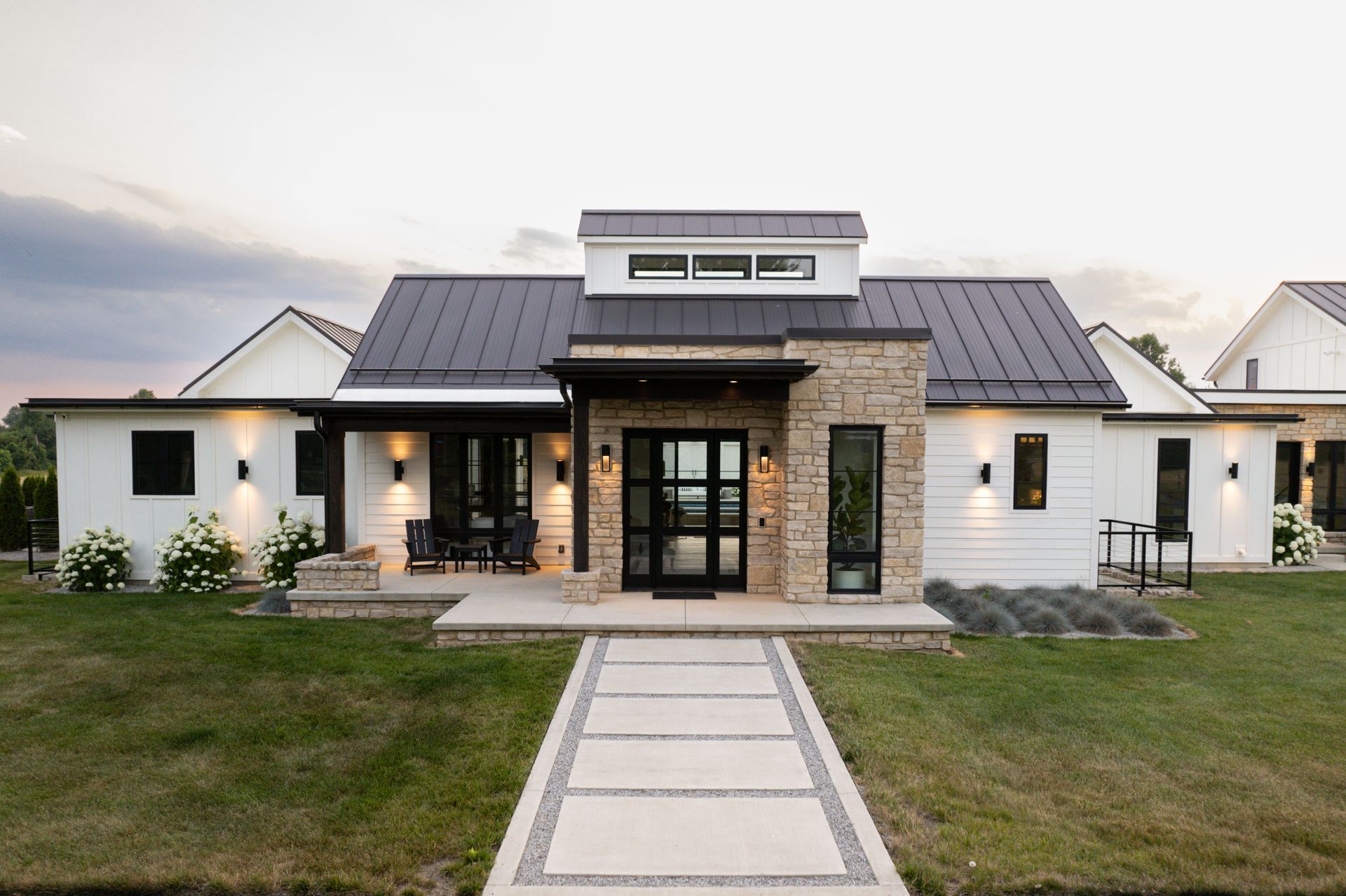 A white house with a black roof and a walkway leading to it.