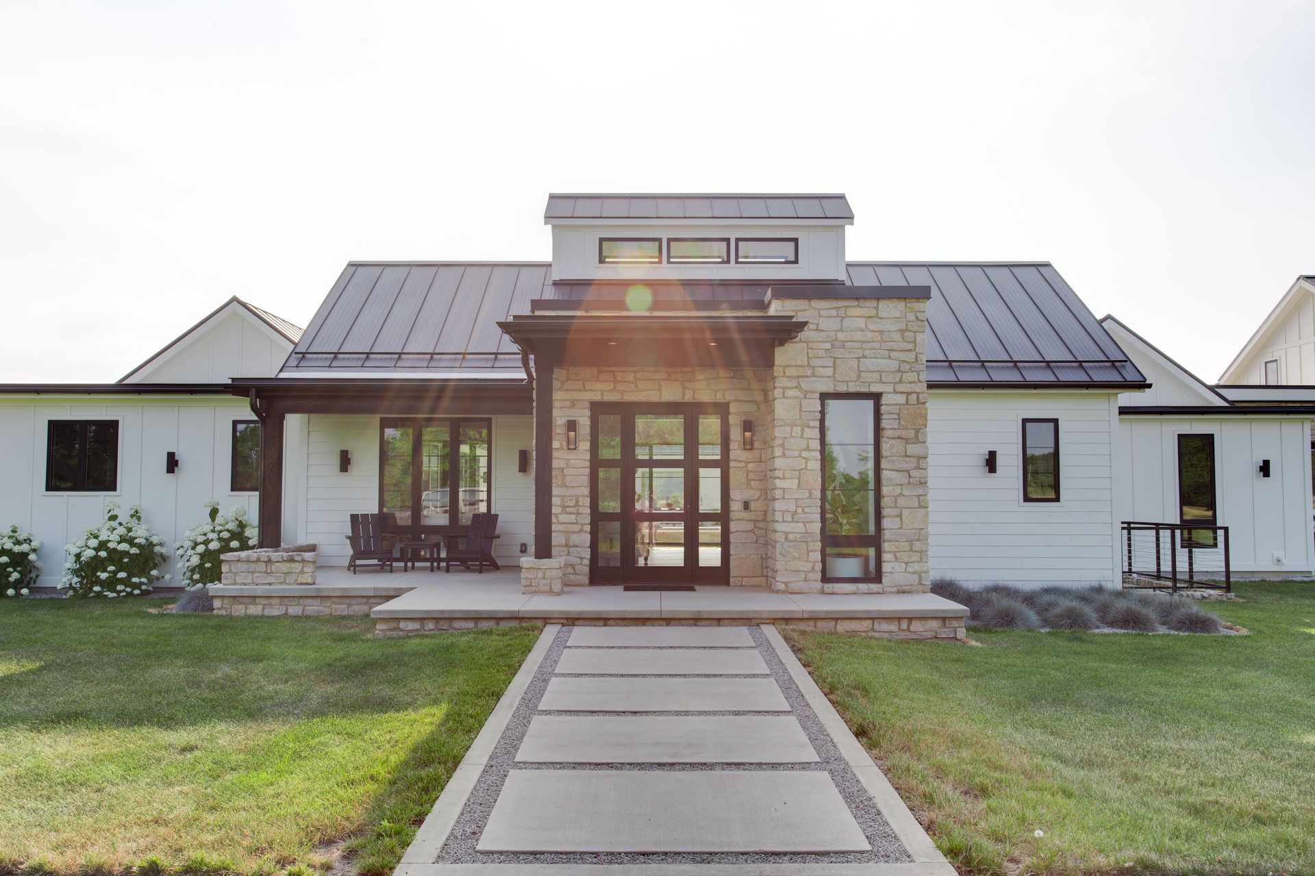 A large white house with a black roof and a walkway leading up to it.