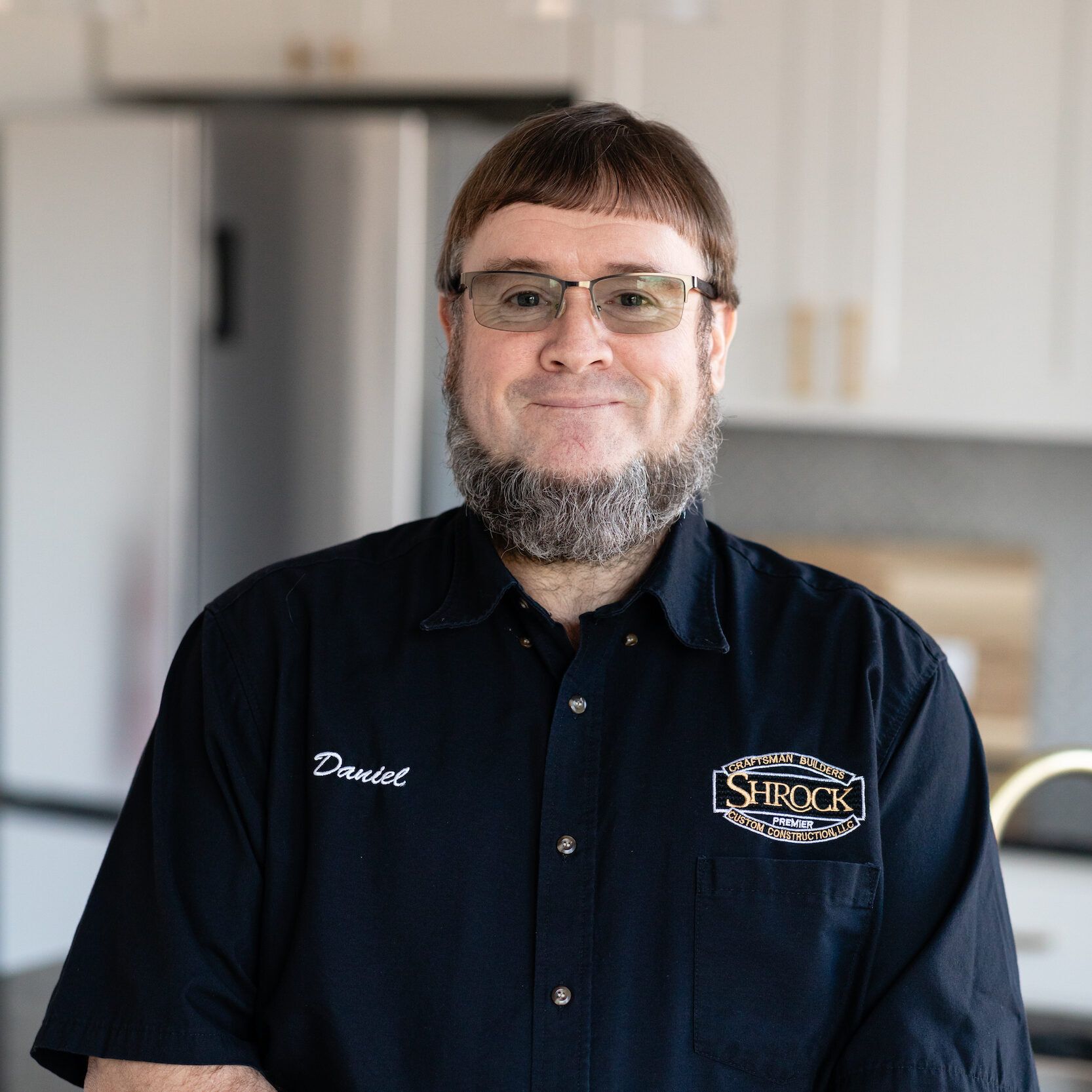 A man with a beard is wearing glasses and a black shirt.