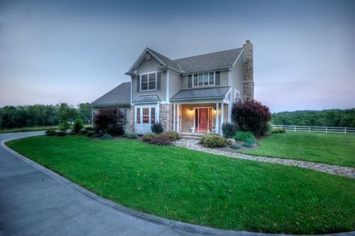 A large house with a lush green lawn and a driveway leading to it.