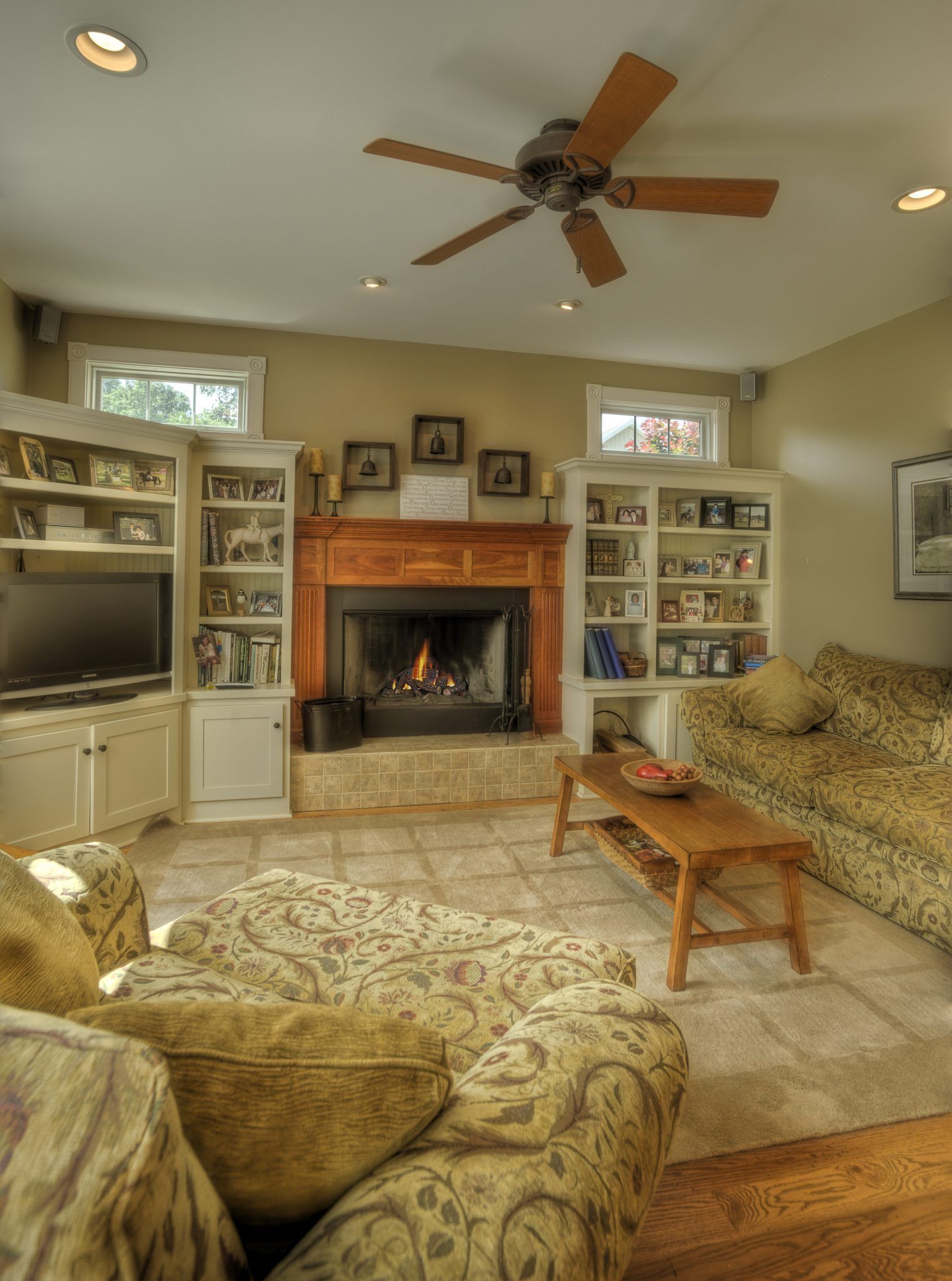 A living room with a fireplace and a ceiling fan.