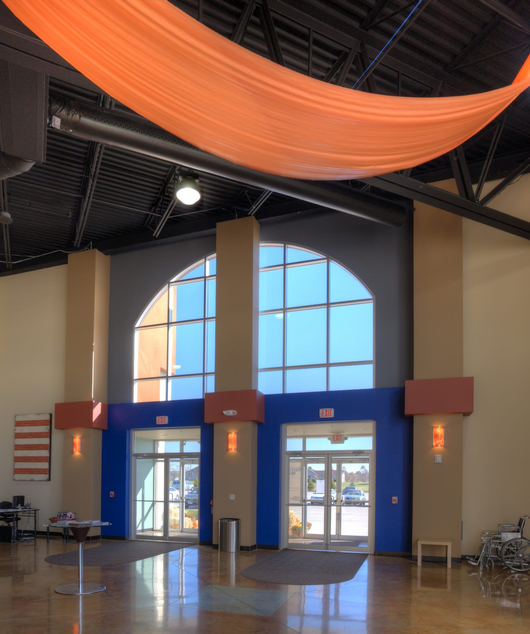 A large room with lots of windows and a large orange cloth hanging from the ceiling.