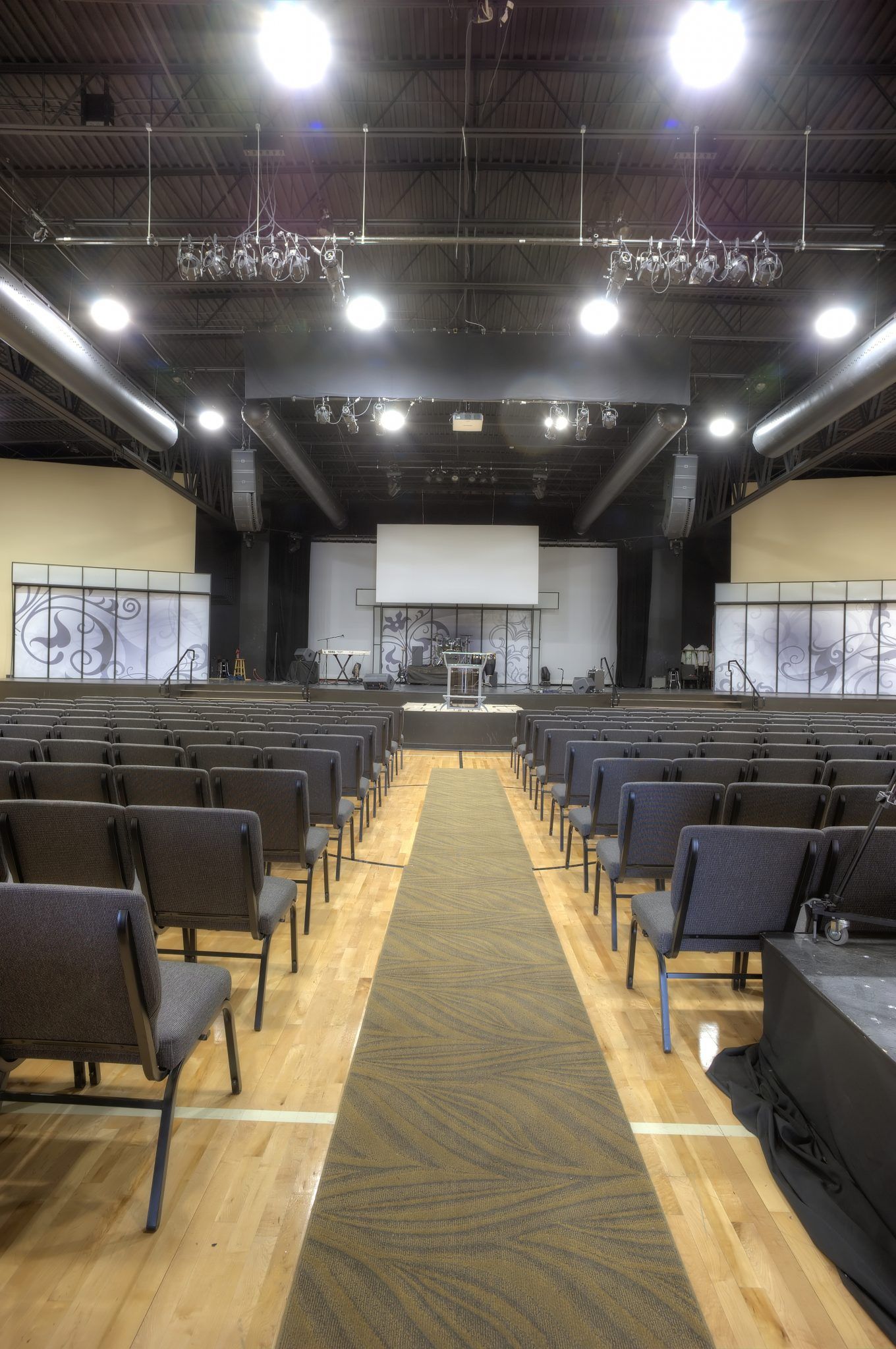 A large auditorium with rows of chairs and a carpet leading to the stage.