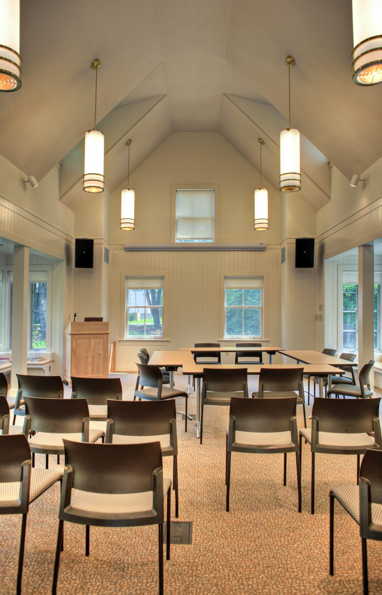 Rows of chairs and tables in a room with a vaulted ceiling.