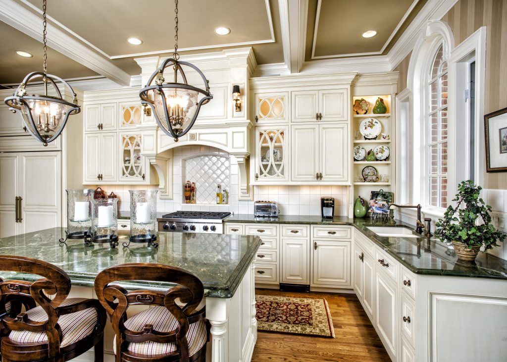 A kitchen with white cabinets, granite counter tops, and a large island.