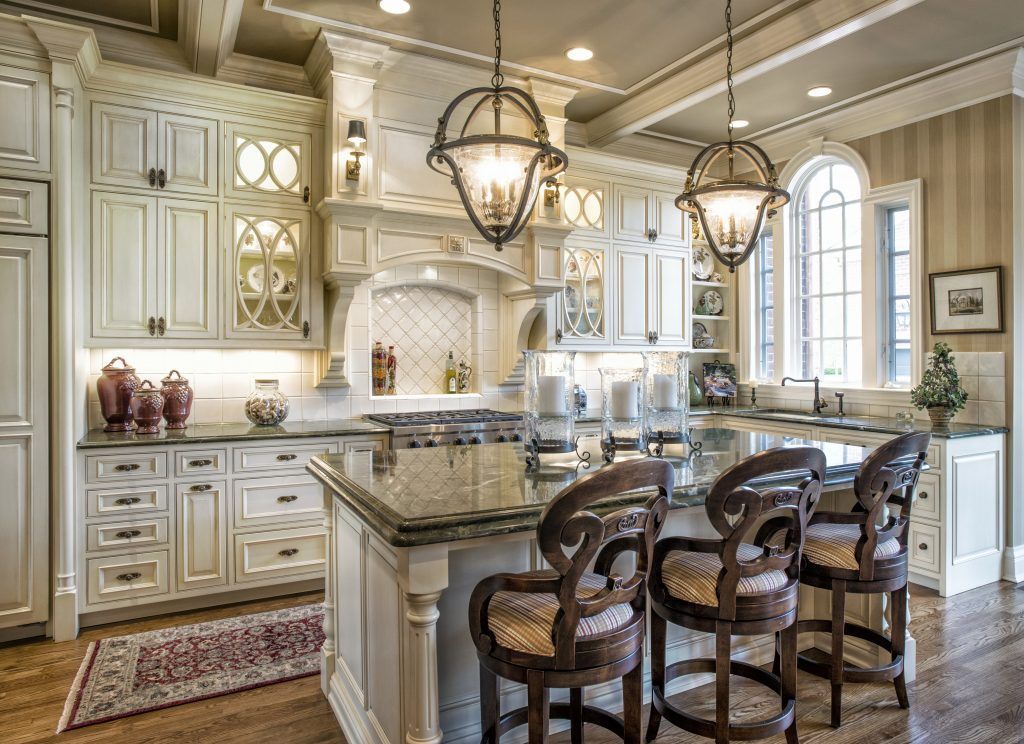 A kitchen with white cabinets, granite counter tops, wood stools, and a large island.