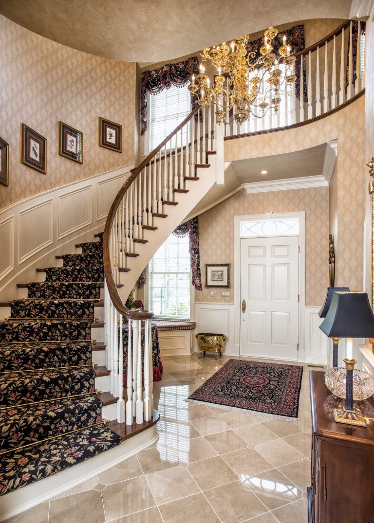 A large hallway with a curved staircase and a chandelier.