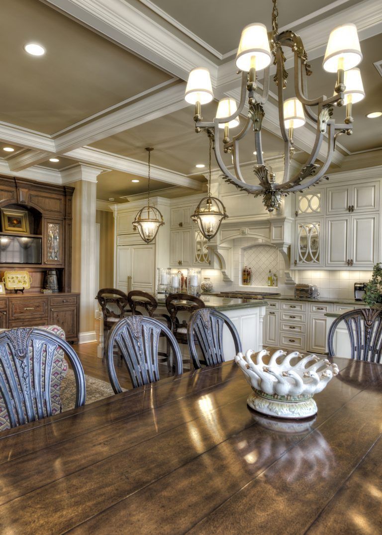 A dining room table with chairs and a chandelier hanging from the ceiling.