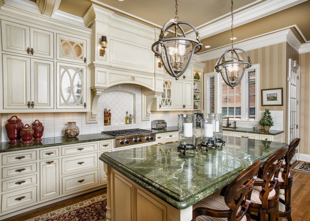 A kitchen with white cabinets, granite counter tops, and a large island.
