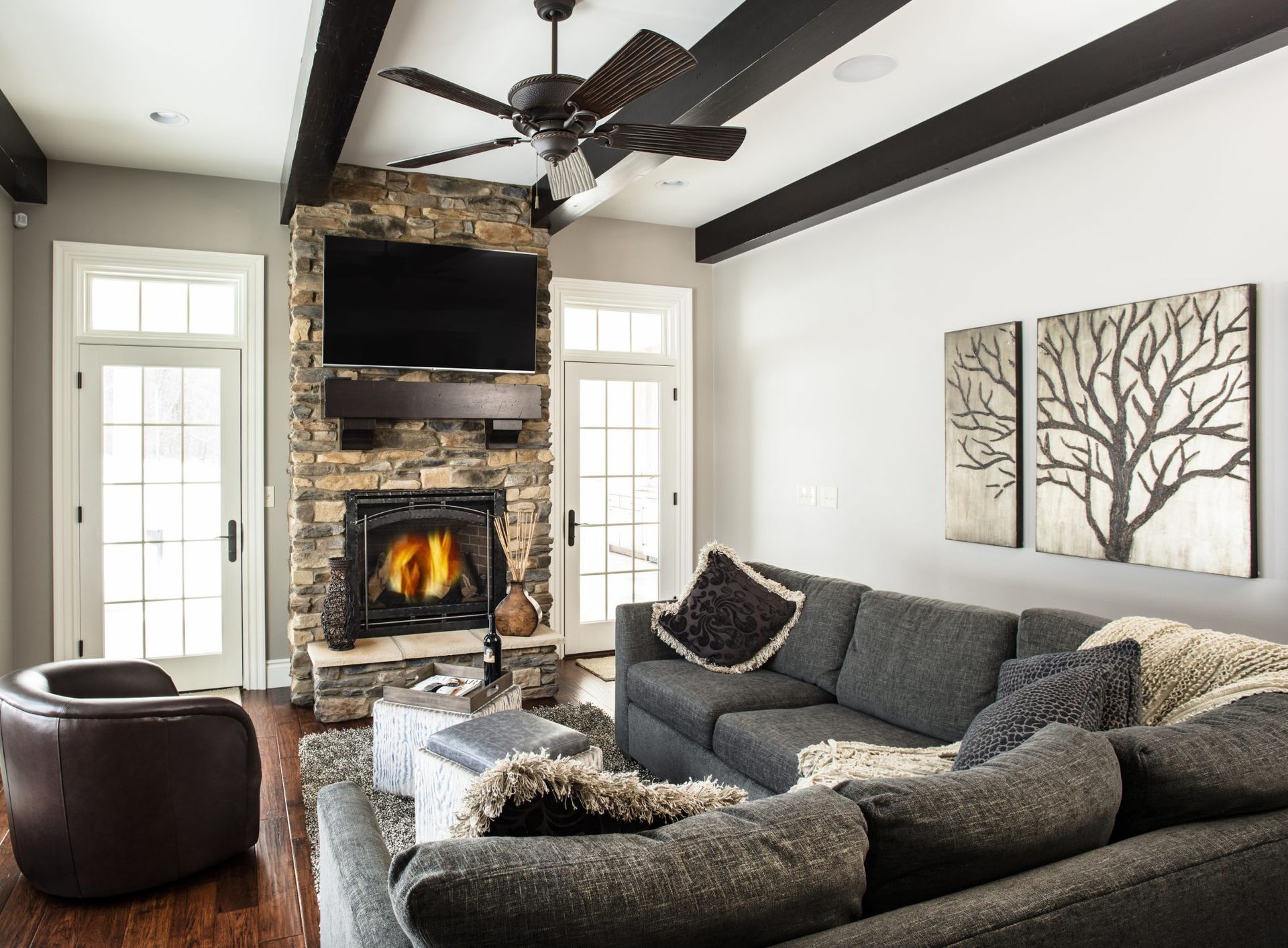 A living room with a couch , fireplace , television and ceiling fan.