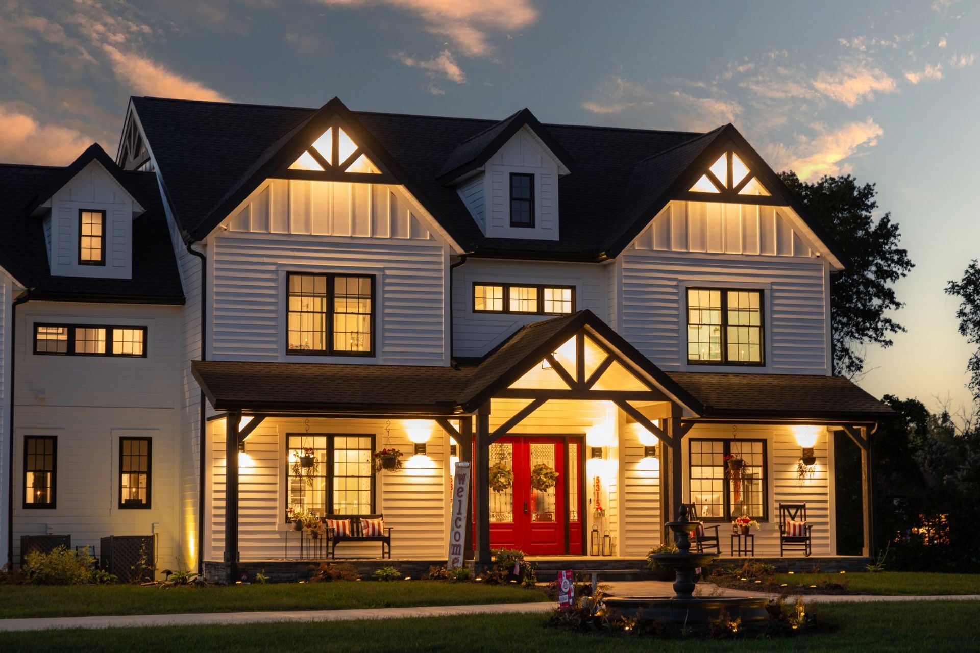 A large white house with a red door is lit up at night.