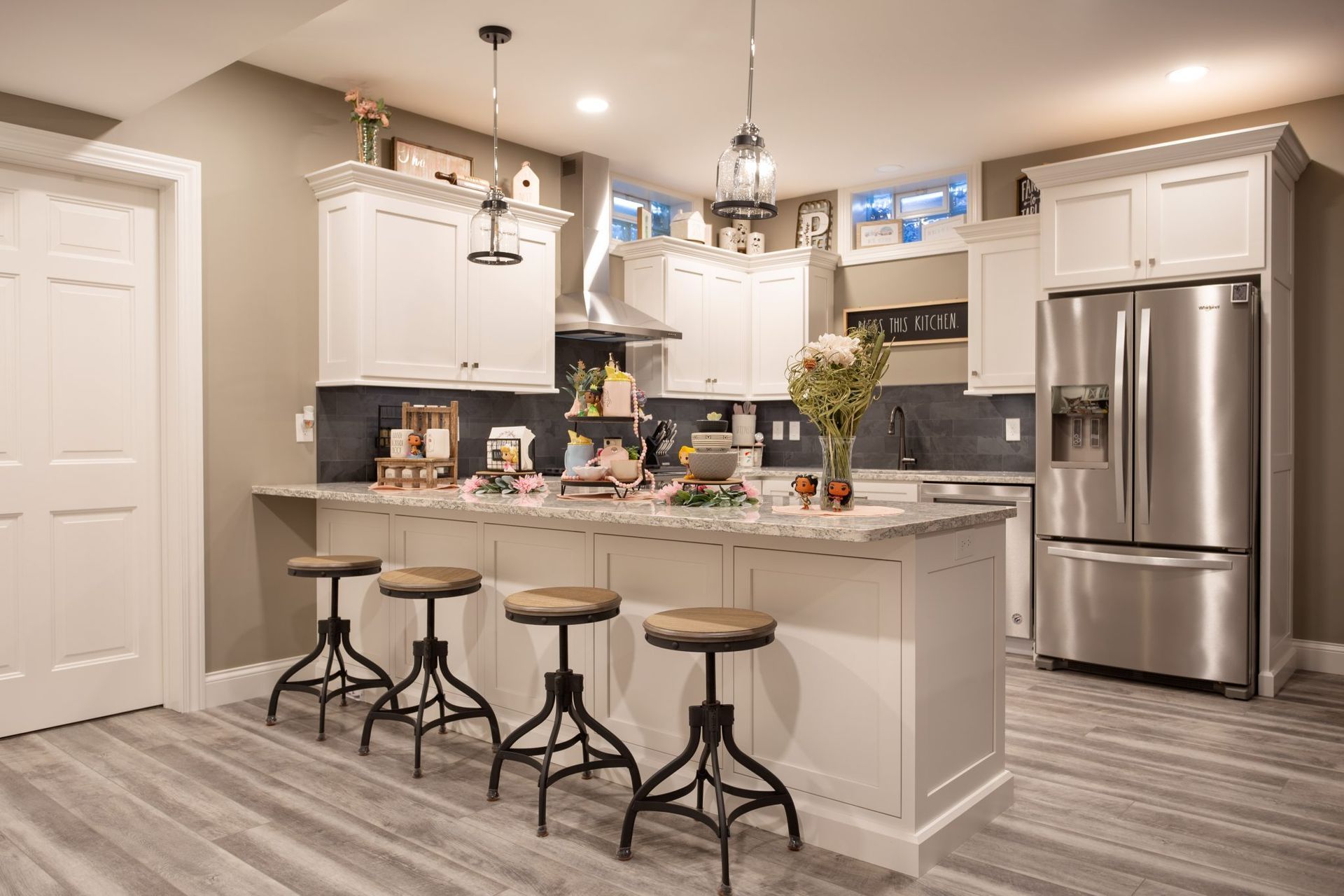 A kitchen with white cabinets , stainless steel appliances , a large island and stools.