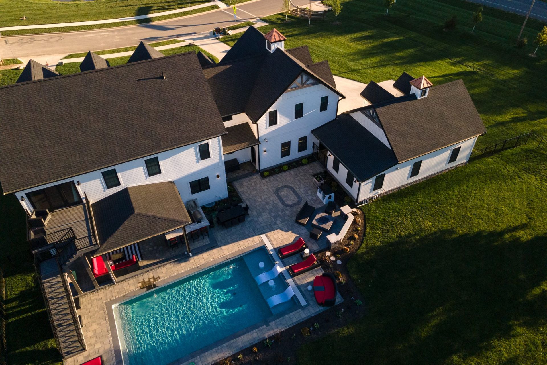 An aerial view of a large house with a swimming pool in front of it.