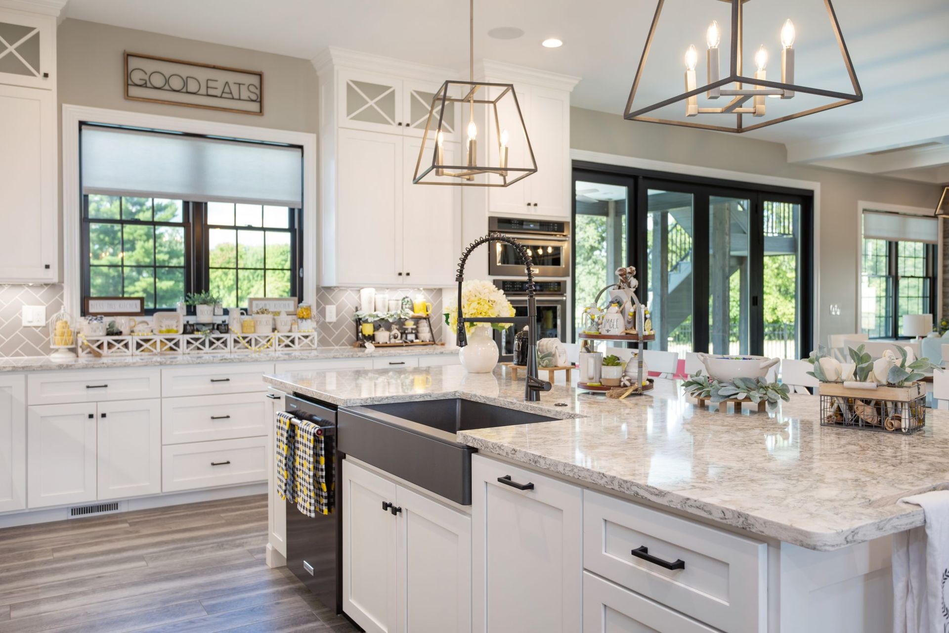 A kitchen with white cabinets , granite counter tops , a sink , and a large island.