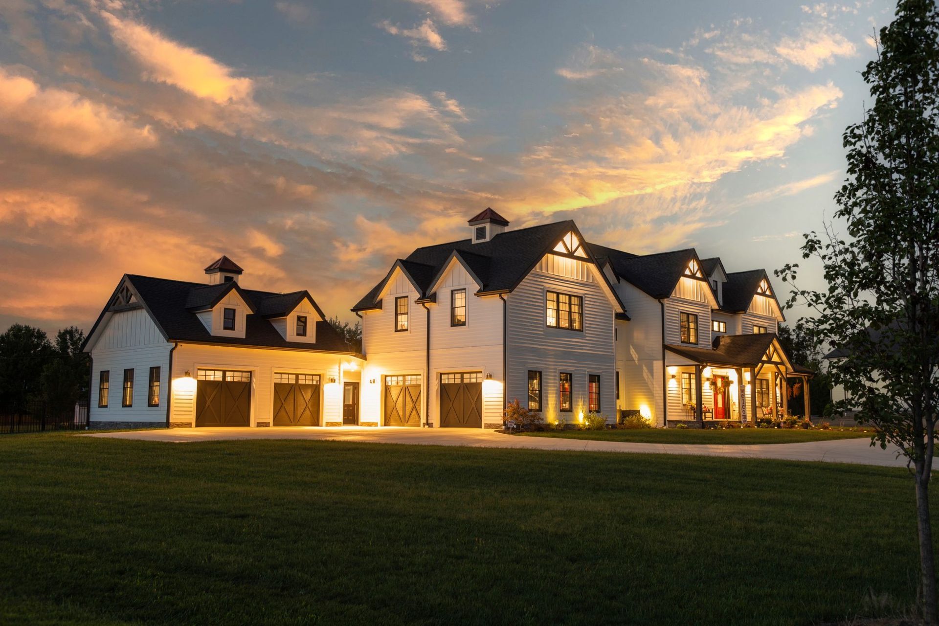 A large white house with a sunset in the background.