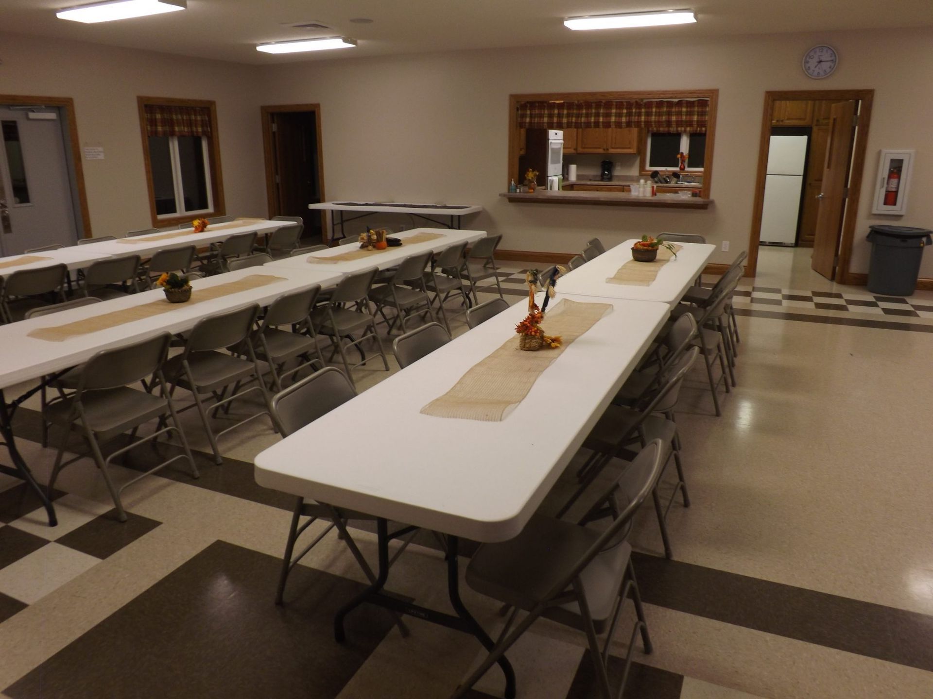 A room with tables and chairs and a clock on the wall.