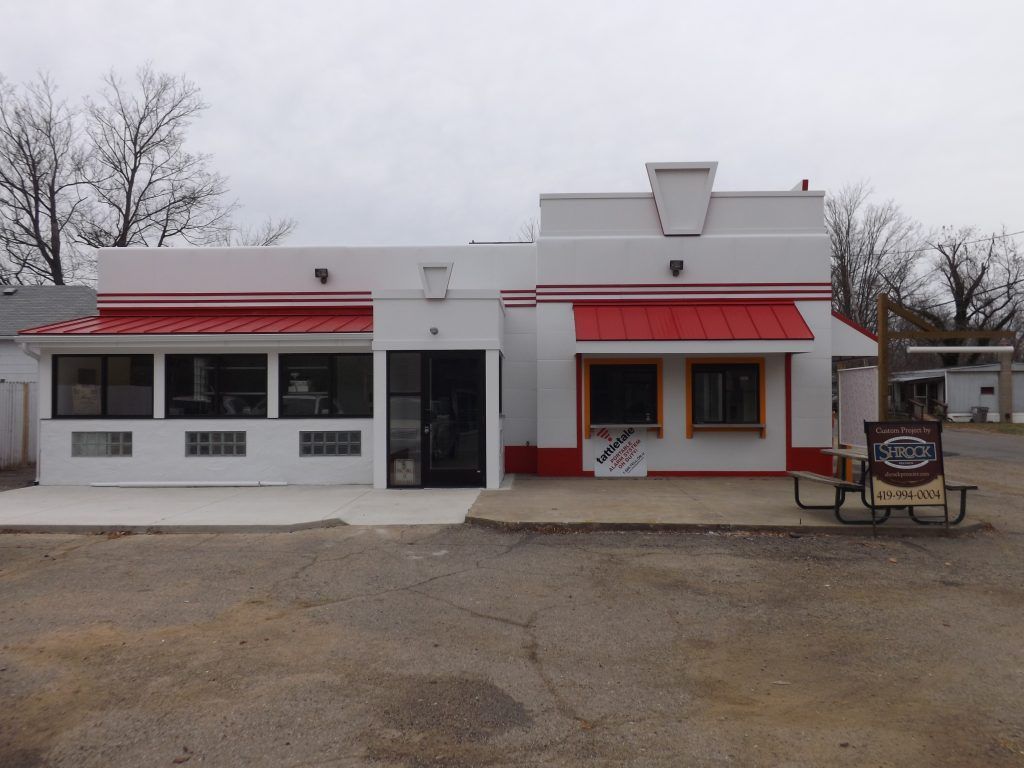 A white building with a red awning and a sign that says ice cream.