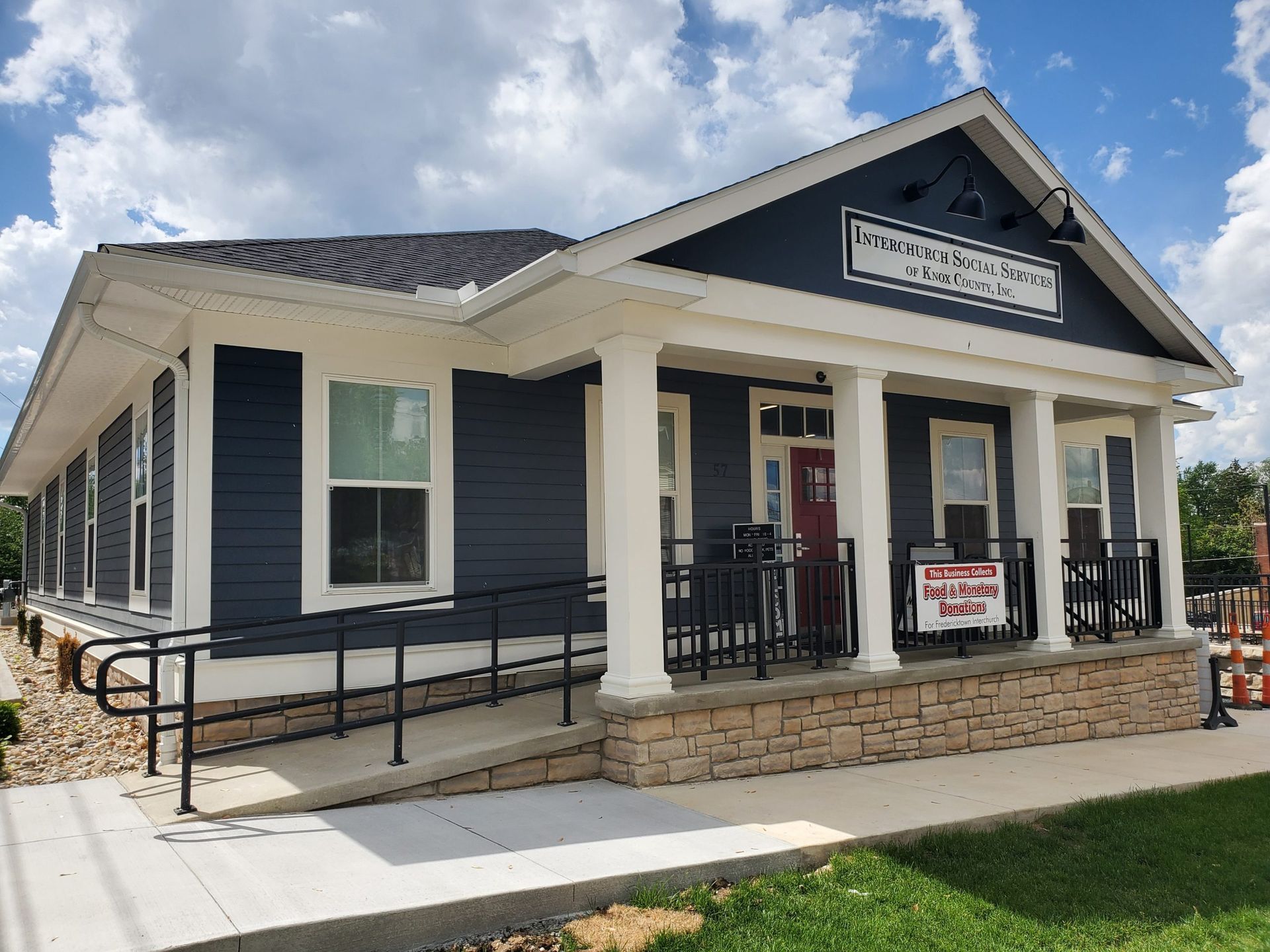 A blue and white house with a porch and a handicap ramp.