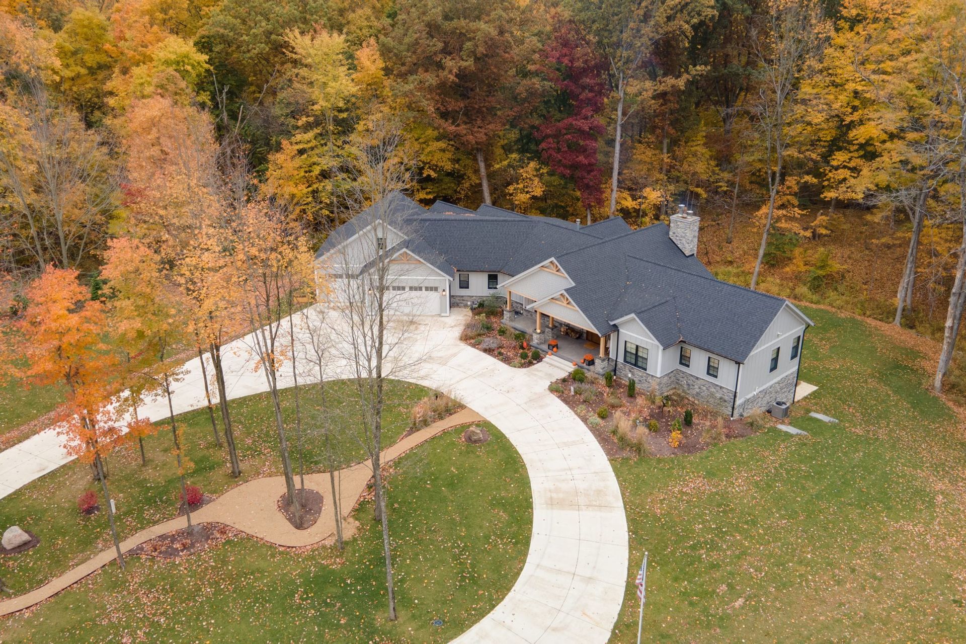An aerial view of a house with a long driveway surrounded by trees.