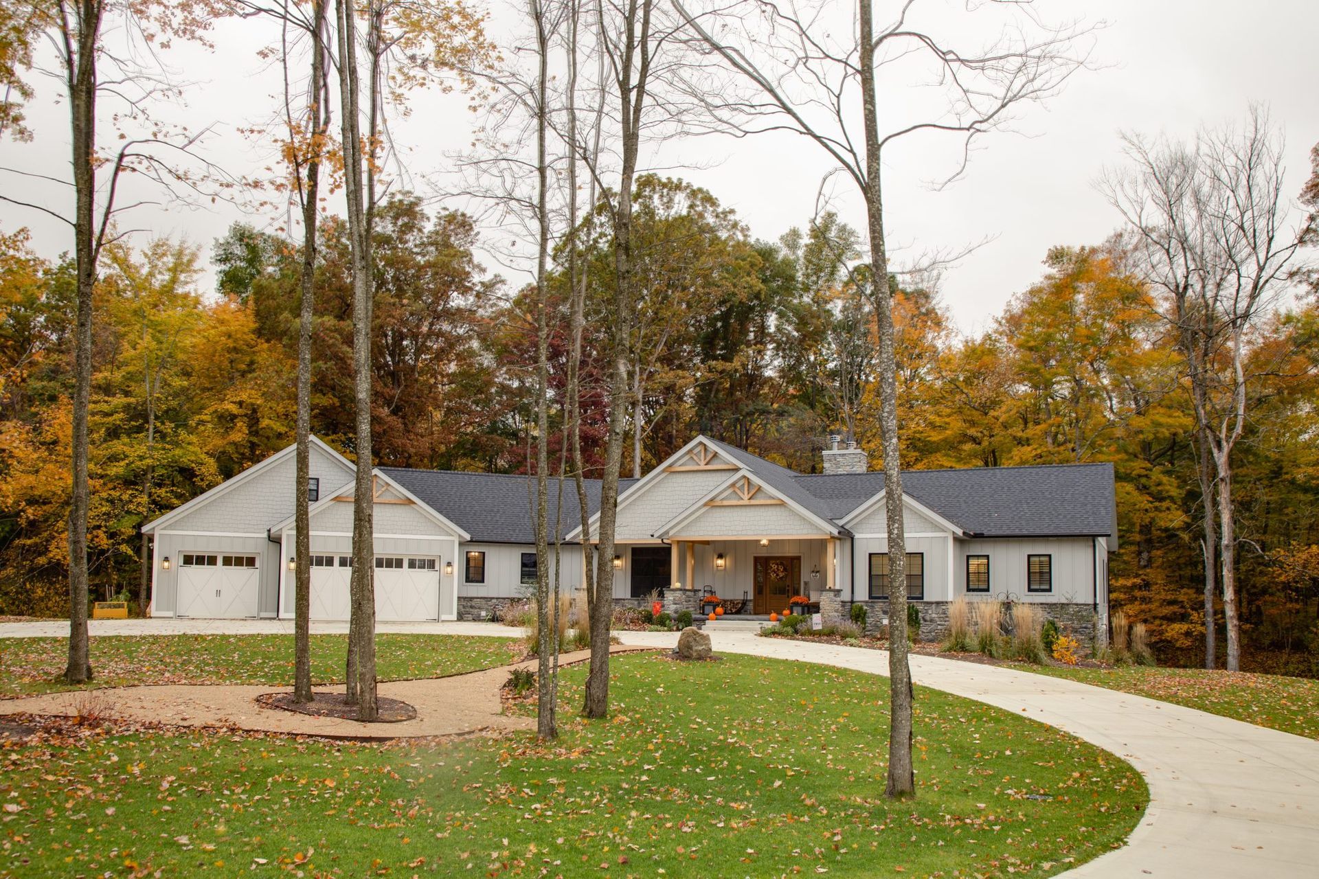 A large white house with a driveway leading to it is surrounded by trees.