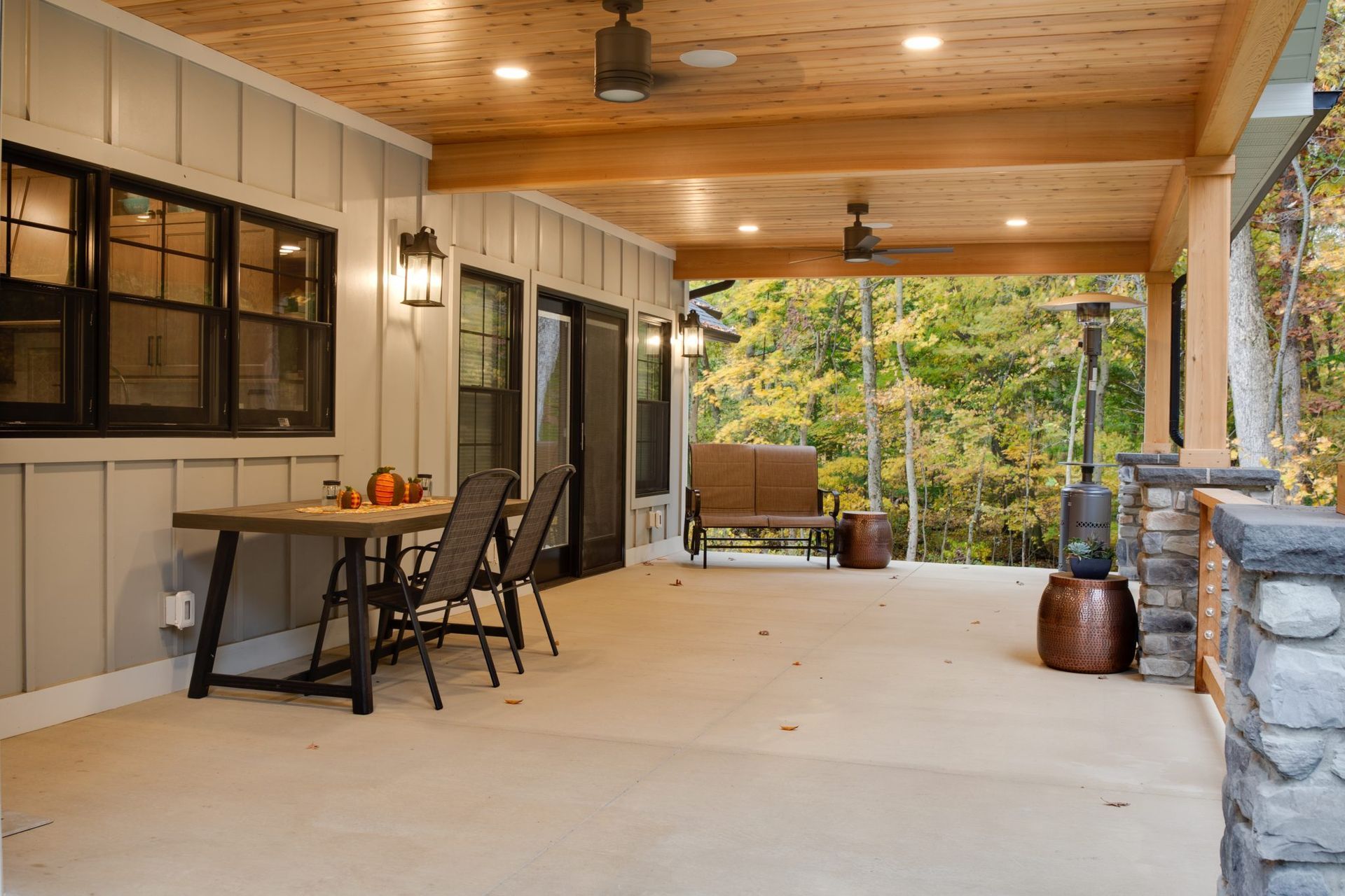 There is a table and chairs on the porch of a house.