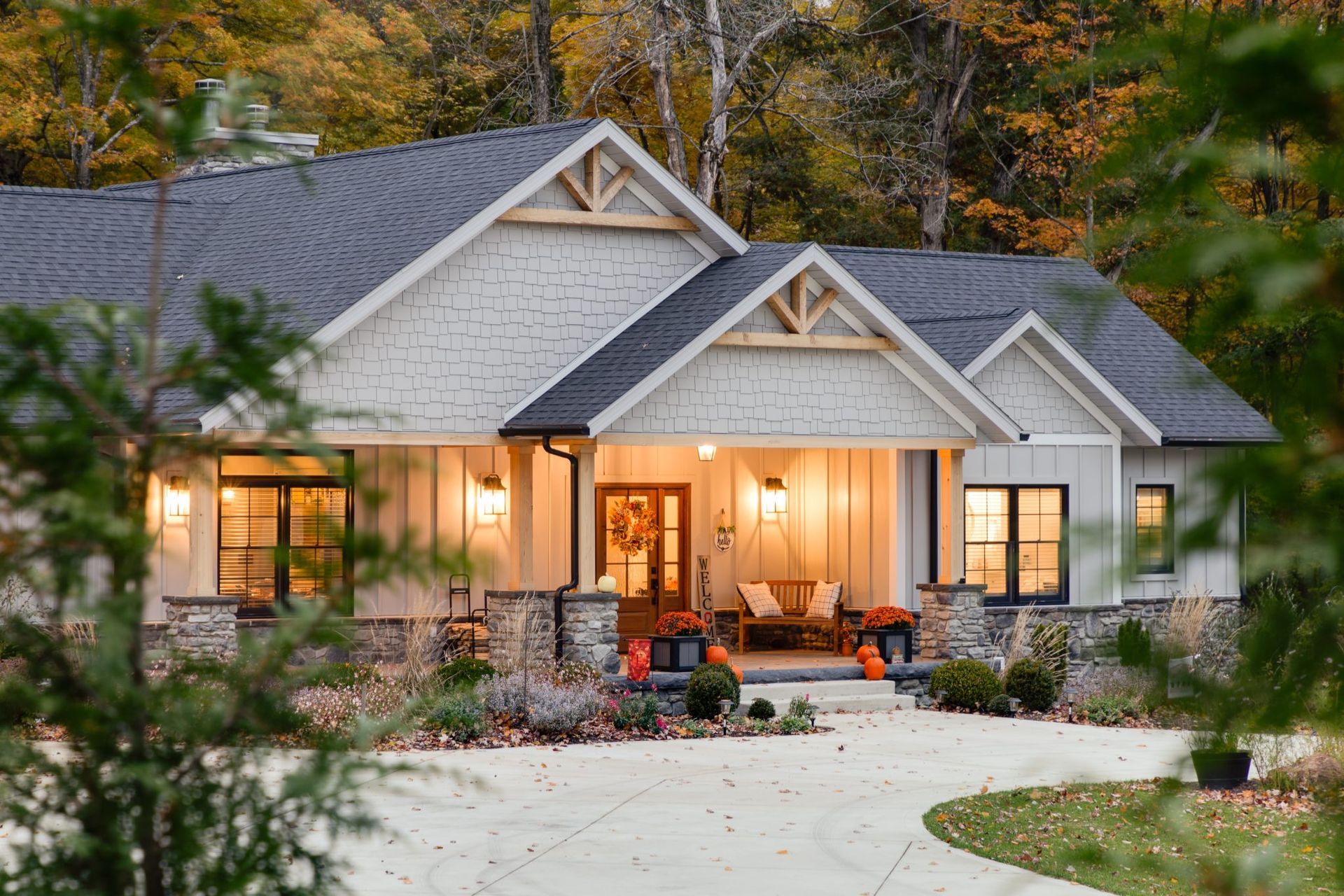 A large white house with a black roof is surrounded by trees.