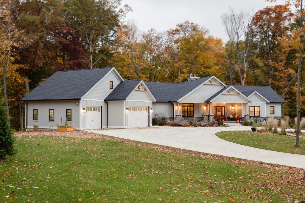 A large white house with a black roof is surrounded by trees.