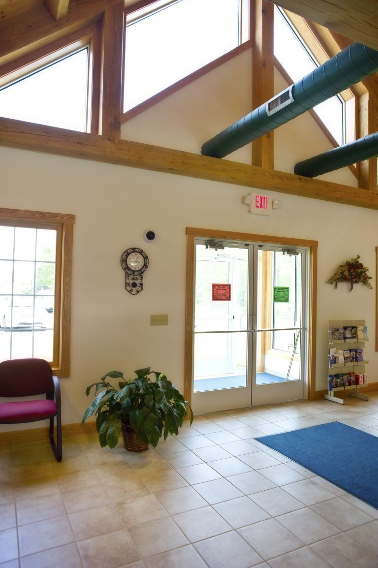 A waiting room with a red chair and a plant.
