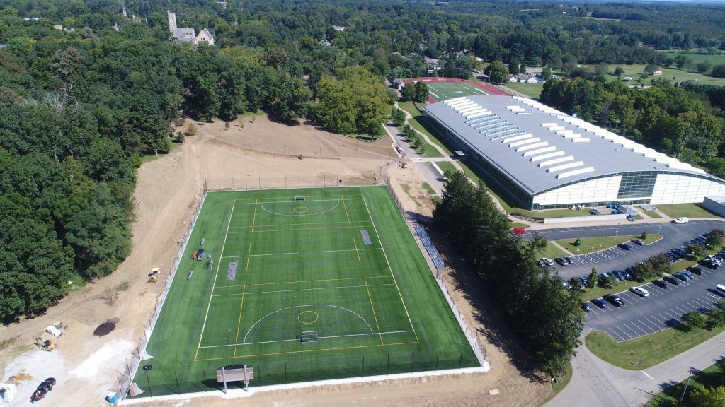 An aerial view of a soccer field with a large building in the background.
