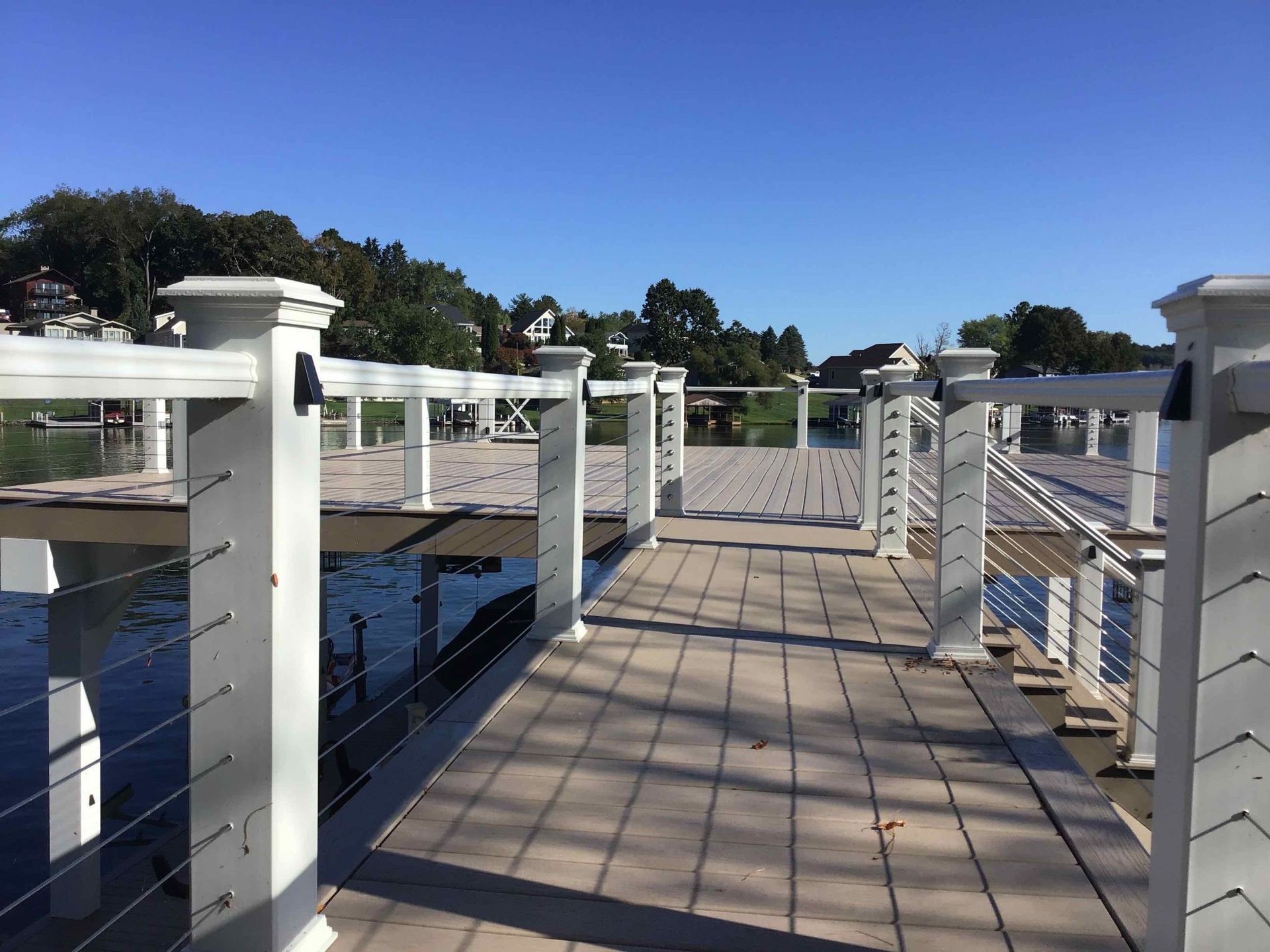 A wooden deck with white railings overlooking a body of water.
