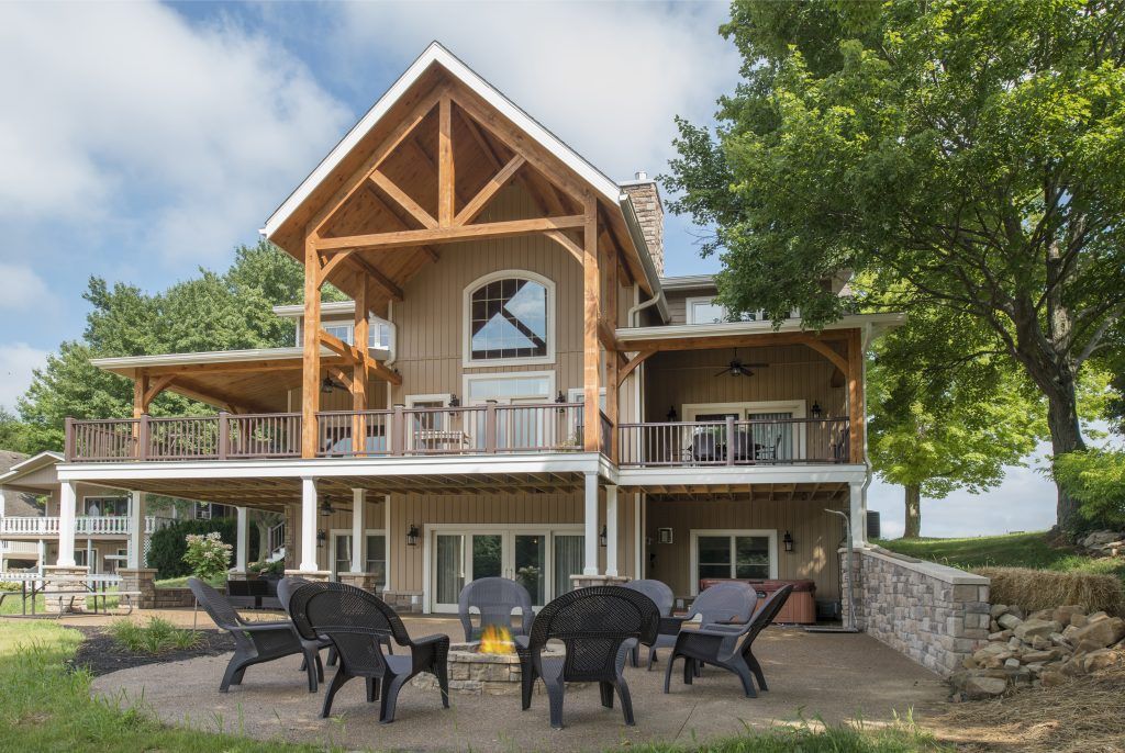 A large house with a patio and fire pit in front of it.