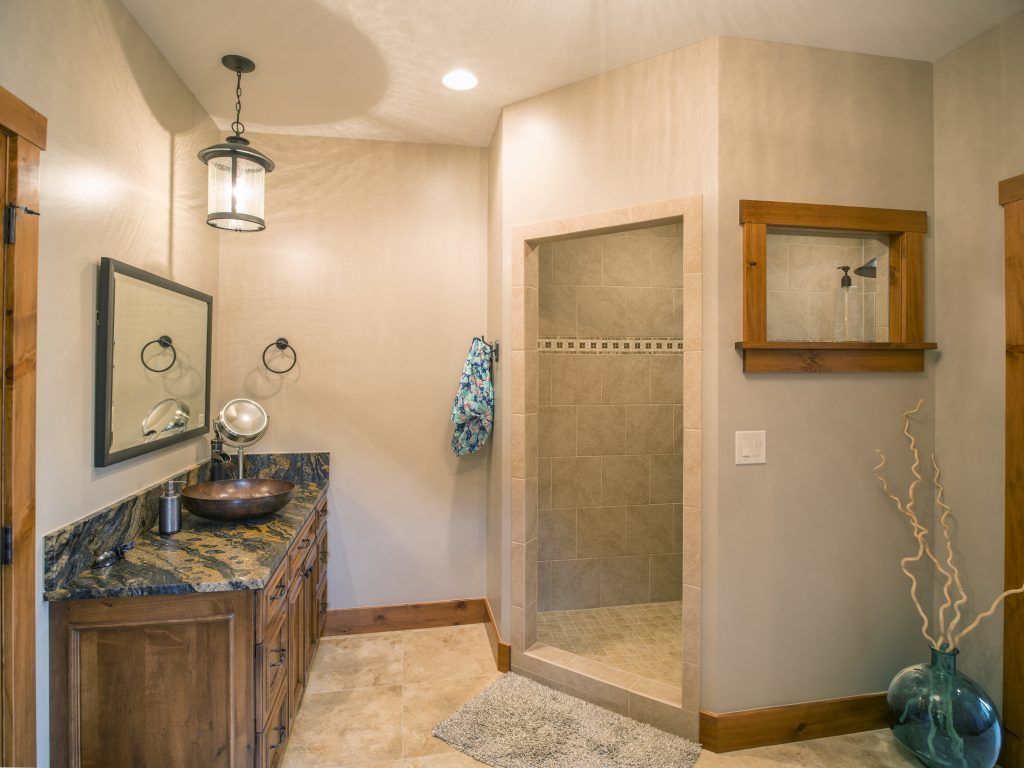 A bathroom with a sink, mirror, and walk in shower.
