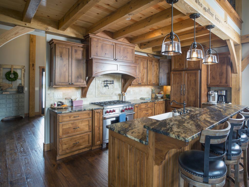 A kitchen with wooden cabinets, granite counter tops, and stainless steel appliances and a large island.