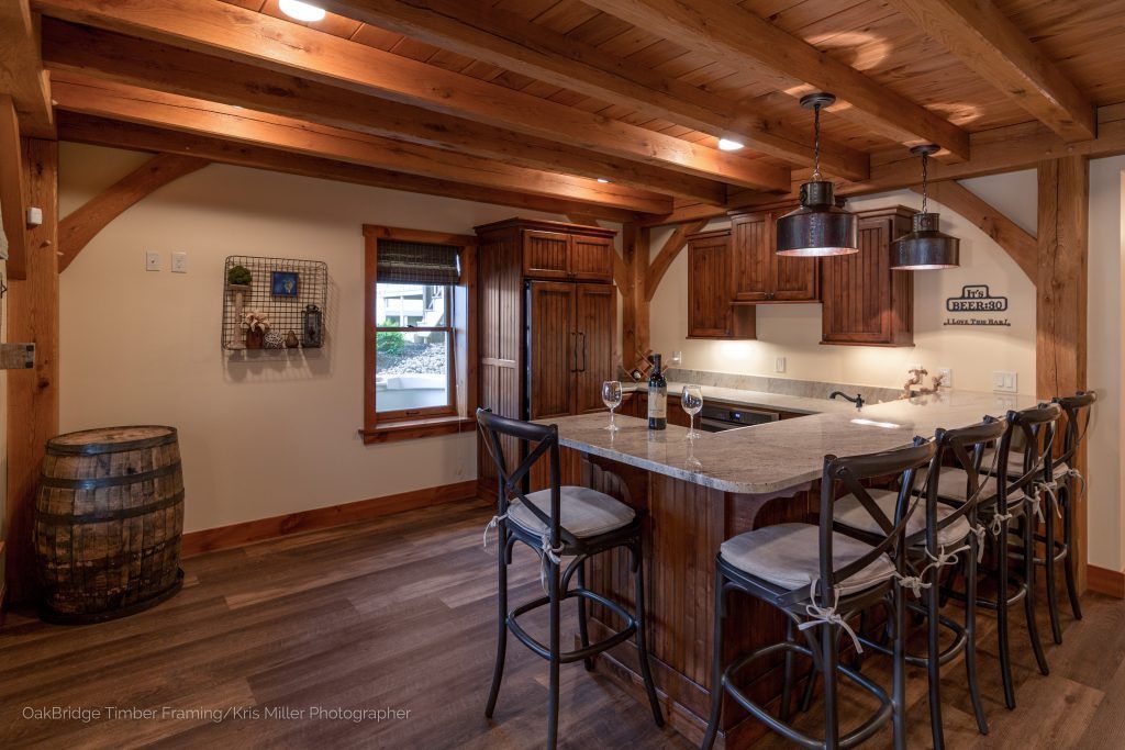 A kitchen with a bar and stools and a barrel in the background.
