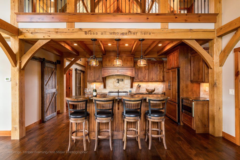 A kitchen with wooden cabinets and stools and a wooden ceiling.
