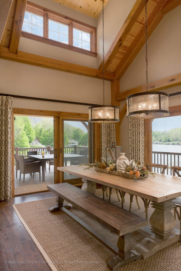 A dining room with a large wooden table and benches sliding doors leading to a deck. 