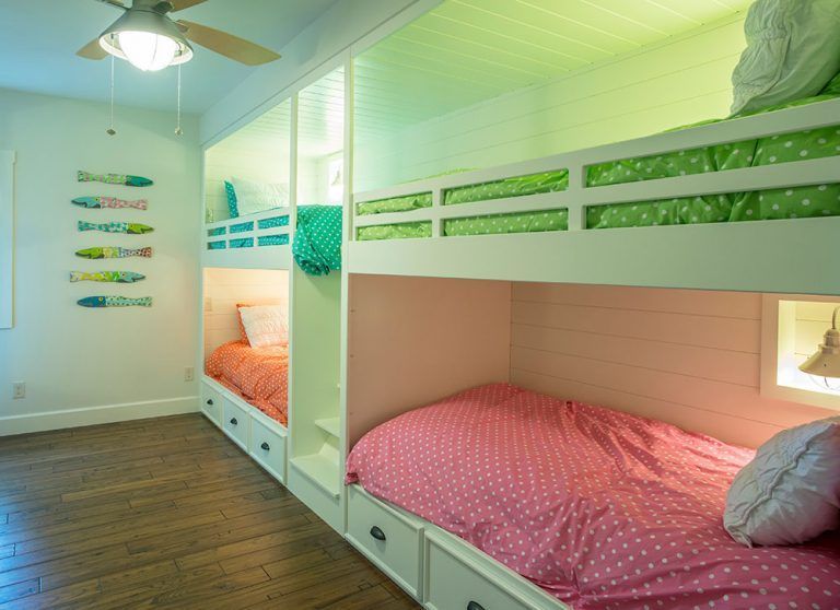 A bedroom with two bunk beds and a ceiling fan.