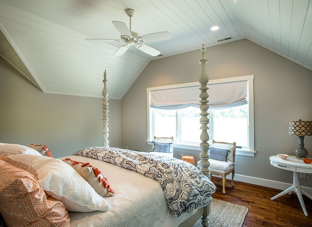 A bedroom with a four poster bed and a ceiling fan.