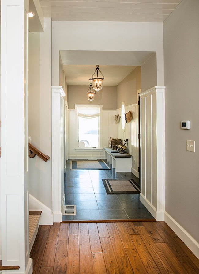 A hallway with hardwood floors leading to a staircase and a window.