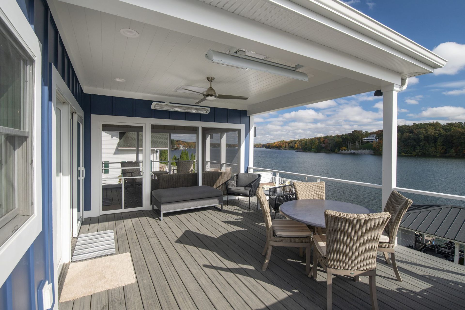 A large deck with a table and chairs overlooking a lake.