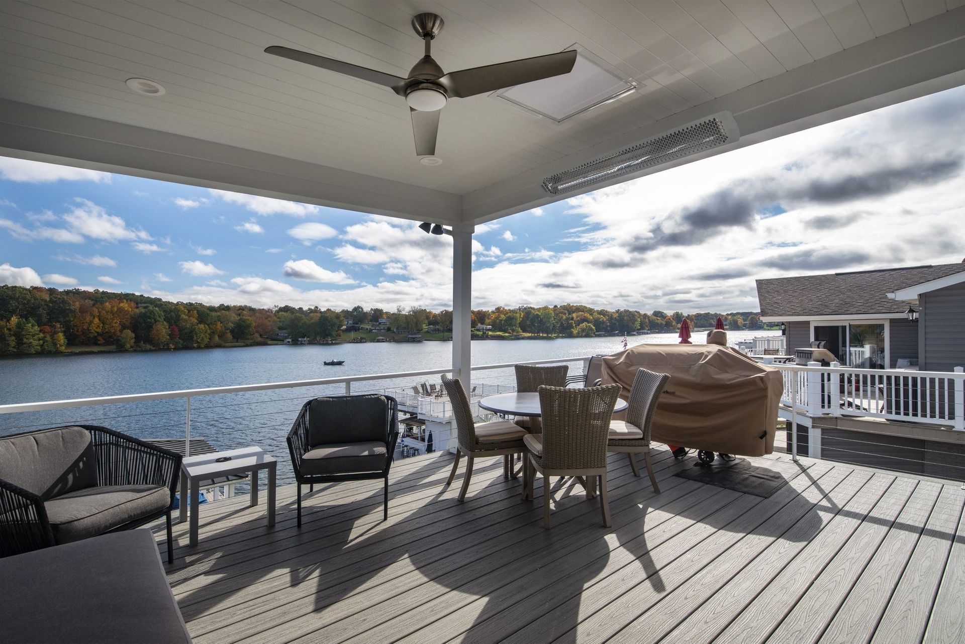 A large deck overlooking a lake with a ceiling fan.